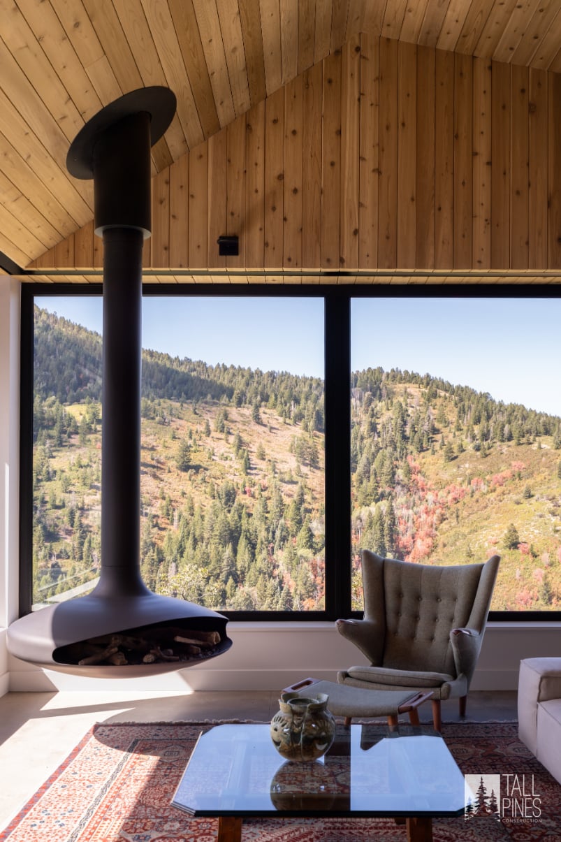 Living Room Area With Modern Wood Burning Stove And Beautiful View Of Park City Mountains. This Highlights The Modern Contemporary Design Of The Toll Canyon Custom Home In Park City, Utah, Built By Tall Pines Construction.