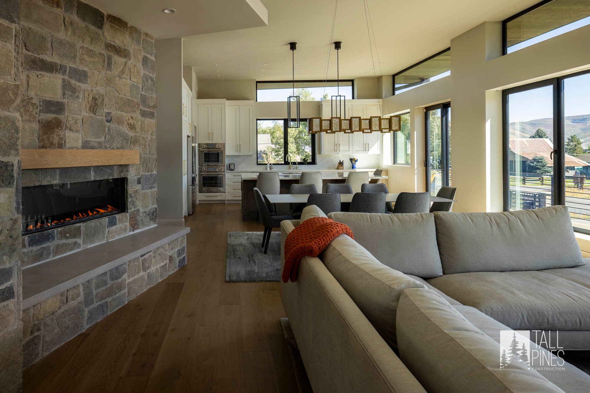 View of living room and dining area with fireplace at the Reservoir Retreat, a modern contemporary custom-built home in Midway, Utah by Tall Pines Construction.