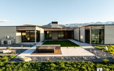 Courtyard view of a modern mountain home in Park City, with expansive glass walls and a landscaped yard.
