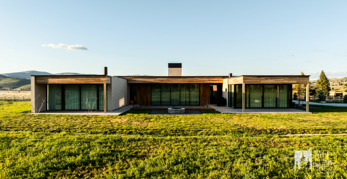 Full front view of a luxury modern home in Park City, surrounded by green open space.