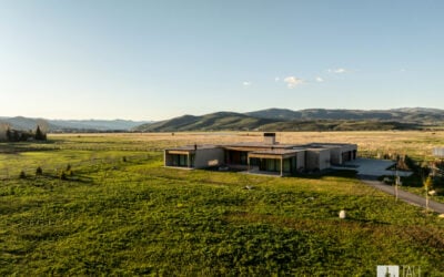 Custom modern home set in a lush green landscape with panoramic mountain views in Park City, Utah.