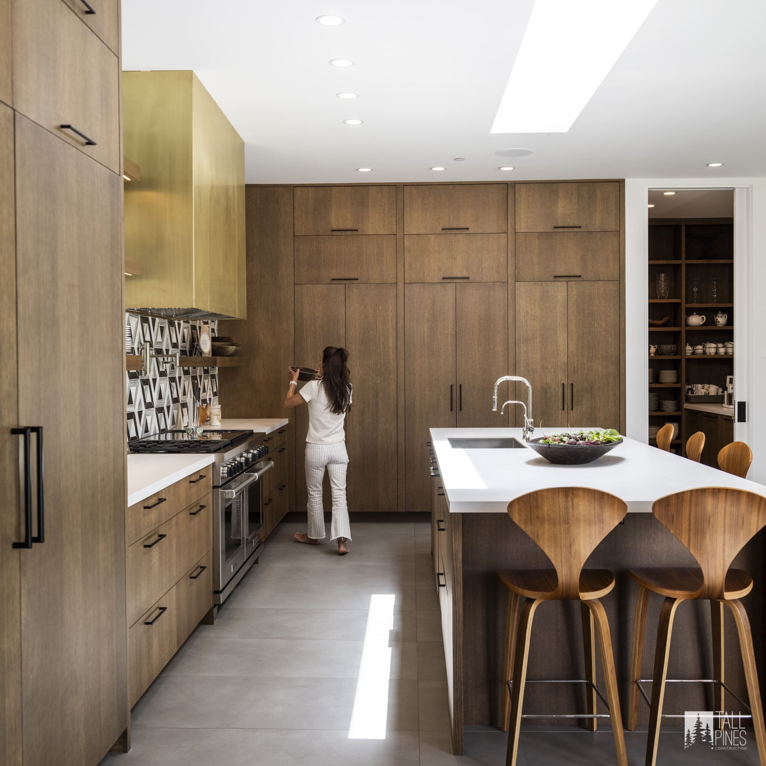 A modern wood kitchen with a brass hood and patterned backsplash for a Park City home builder project by Tall Pines Construction in Park City, Utah.