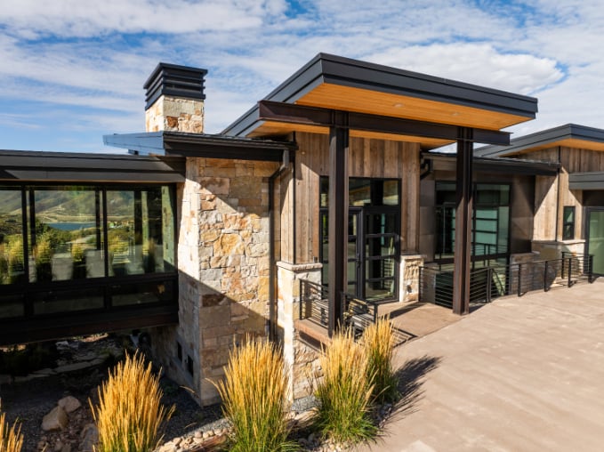 Contemporary Mountain Home Exterior in Park City A contemporary mountain-style home exterior in Park City with stone accents, wood siding, and covered outdoor spaces that blend modern design with Utah’s natural surroundings.