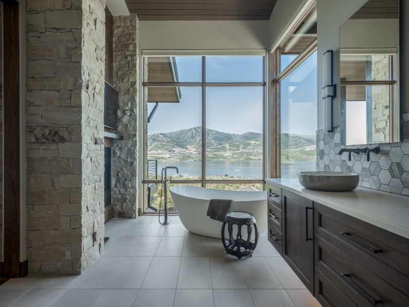Luxury Bathroom with Mountain Views in Custom Home A serene custom bathroom with a freestanding tub and expansive windows framing mountain views, showcasing Tall Pines Construction’s focus on comfort and refined design.