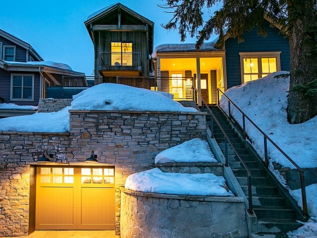 Winter Exterior with Custom Lighting and Stonework A luxury Park City home exterior in winter showcasing stone retaining walls, exterior lighting, and a garage entrance designed for both function and curb appeal.