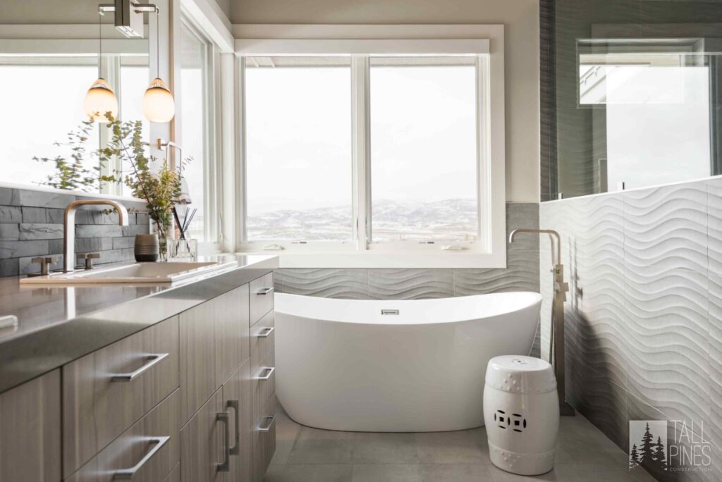 Luxury ensuite bathroom with a freestanding soaking tub, textured wall tile, and mountain-inspired contemporary finishes.