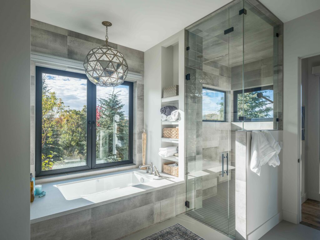 Spa-inspired bathroom with a soaking tub, frameless glass shower, natural light, and mountain modern finishes.
