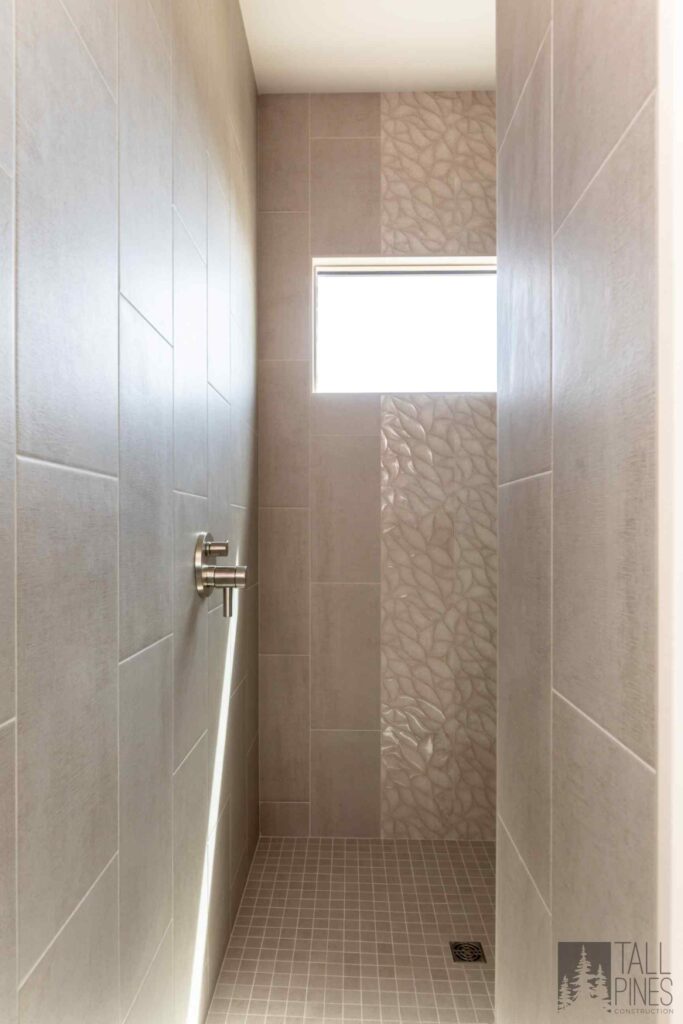 Custom walk-in shower with textured tile, built-in niche, and a clean modern bathroom design.