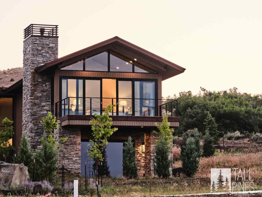 Luxury Park City custom home featuring natural stone, expansive windows, and contemporary mountain architecture at sunset.