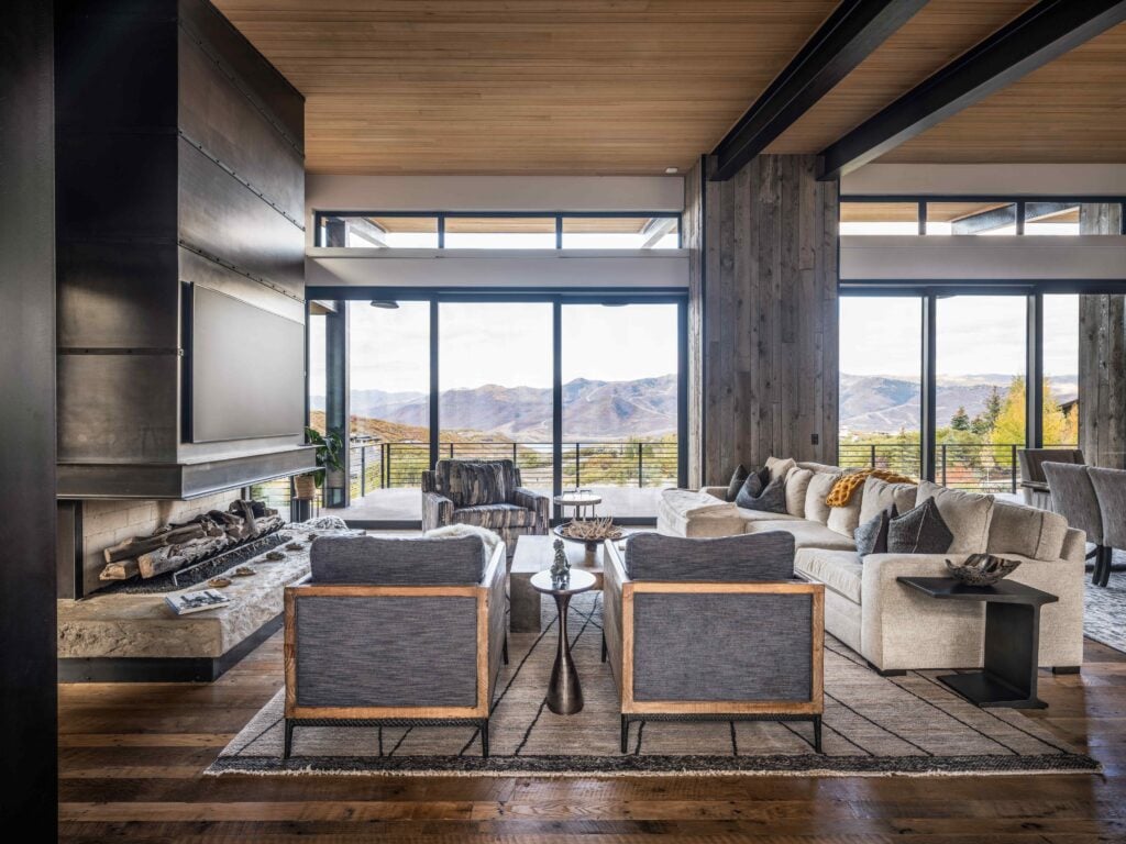 Spacious great room inside a Park City custom home featuring floor-to-ceiling windows, a modern fireplace, and panoramic mountain views.