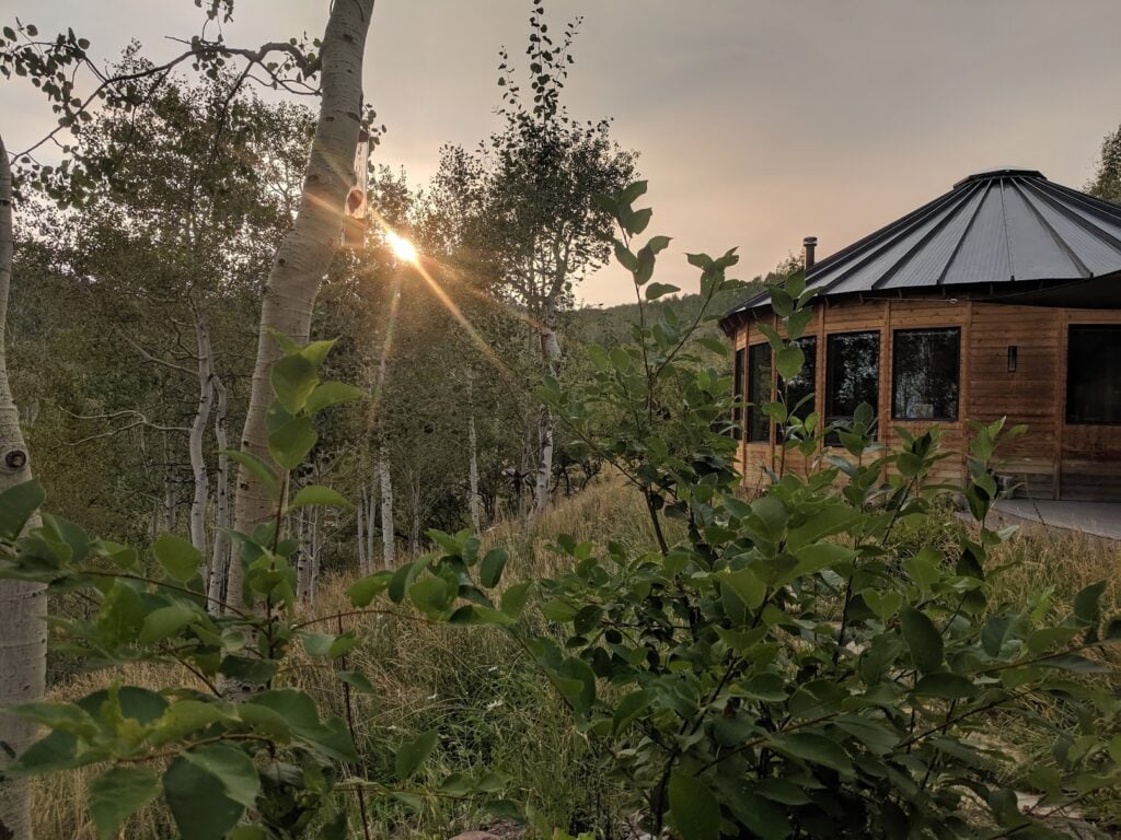 Luxury Park City yurt surrounded by aspen trees at sunset, showcasing a custom mountain retreat designed for four-season living.
