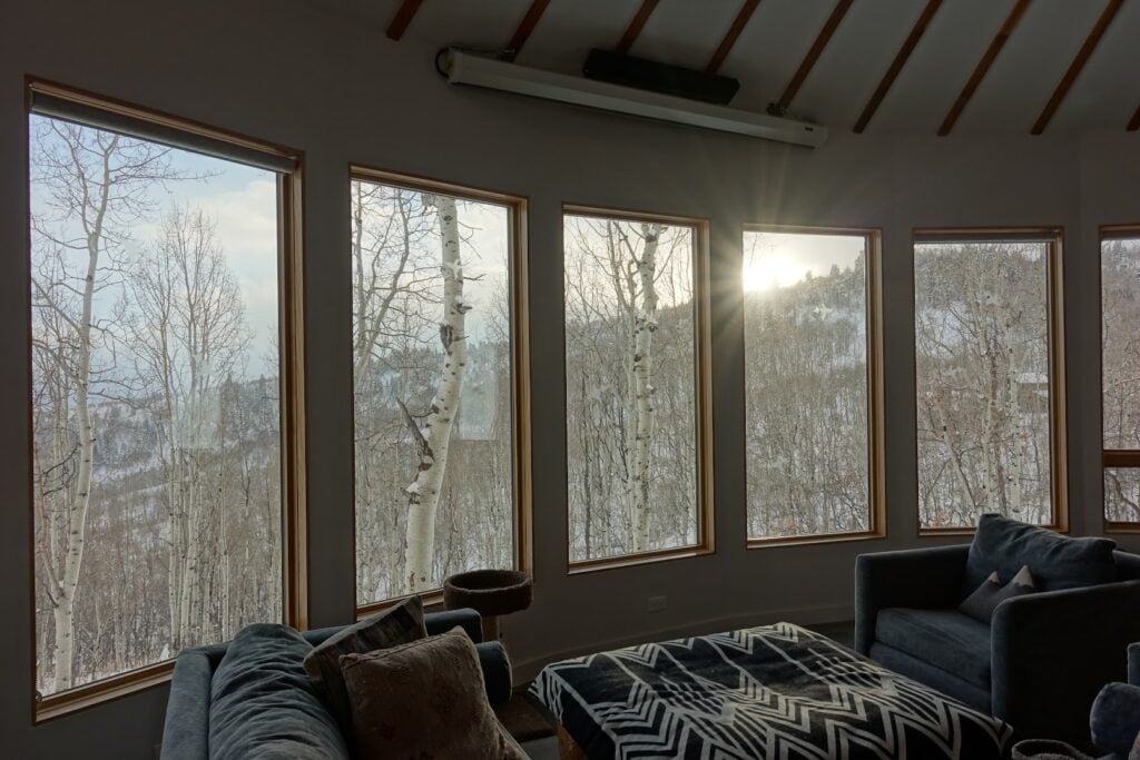 Living room inside a Park City yurt featuring floor-to-ceiling windows with panoramic views of the surrounding aspen forest.