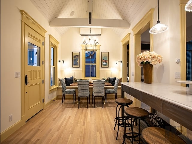 Warm dining area in a custom mountain home featuring wood floors, vaulted ceilings, contemporary lighting, and built-in seating.