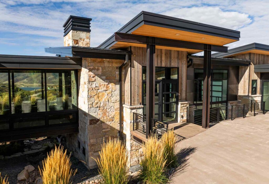Modern mountain home exterior featuring natural stone, wood siding, steel details, and expansive windows suited to the Tuhaye aesthetic.