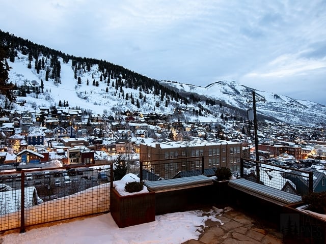 Snow-covered Park City and surrounding ski slopes viewed from the outdoor living area of a custom mountain home.