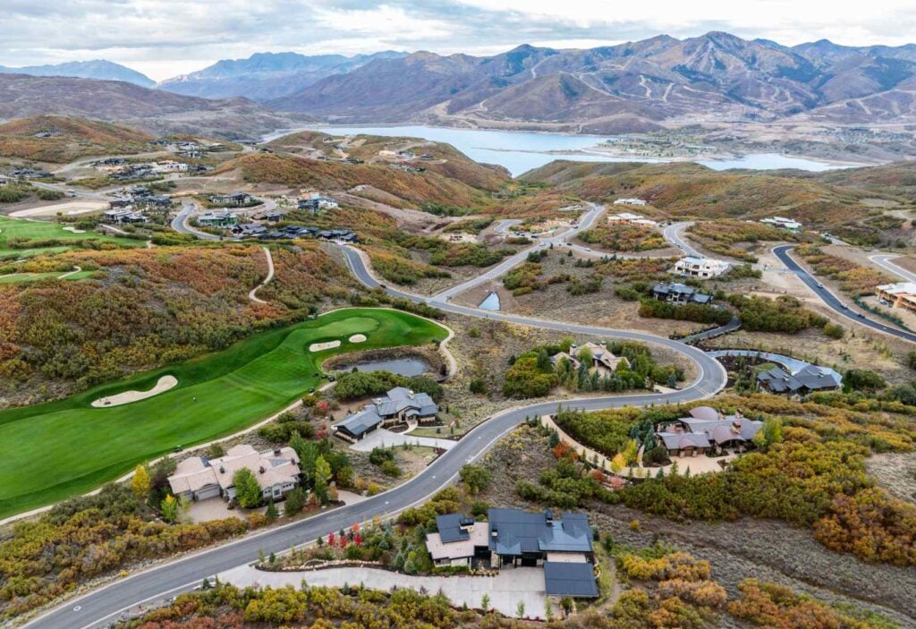 Aerial view of a modern custom mountain home surrounded by the rolling hills and fall landscape of Tuhaye.