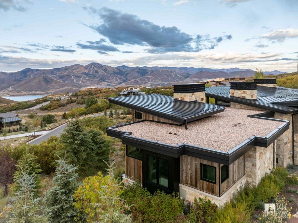 Mountain modern home in Park City featuring stone, natural wood, metal rooflines, and views of the surrounding mountains.