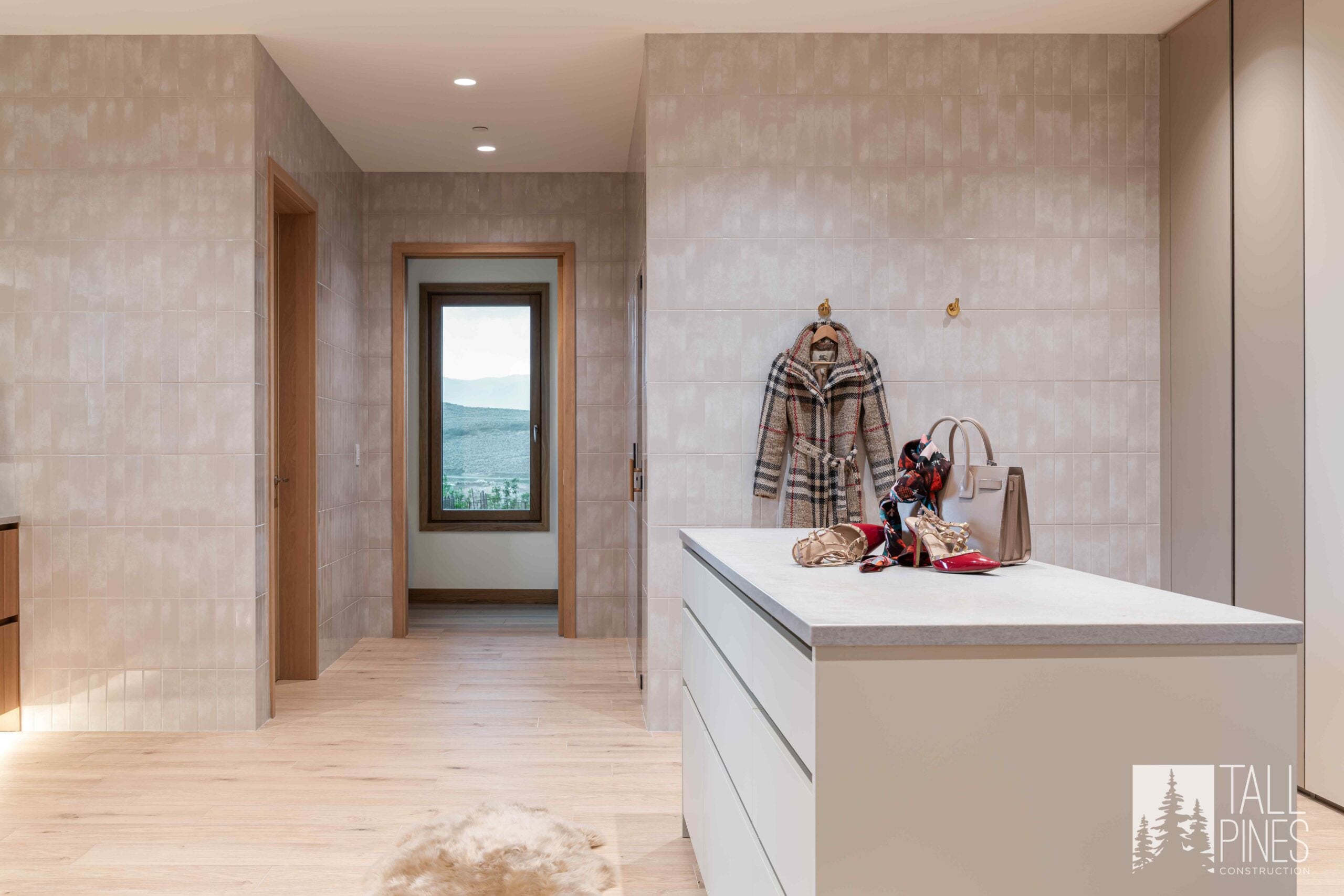 Spacious dressing room at Ridgeline Light with a large center island, custom storage and soft neutral tile surrounding the space.